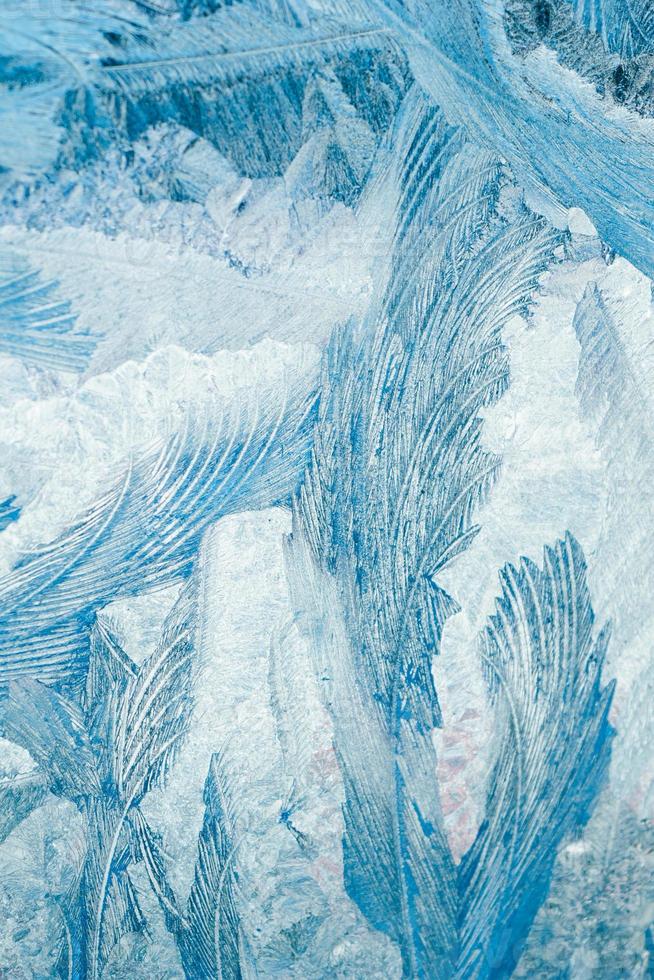 Winter frosty patterns on glass. Christmas festive background. Ice crystals on window. photo