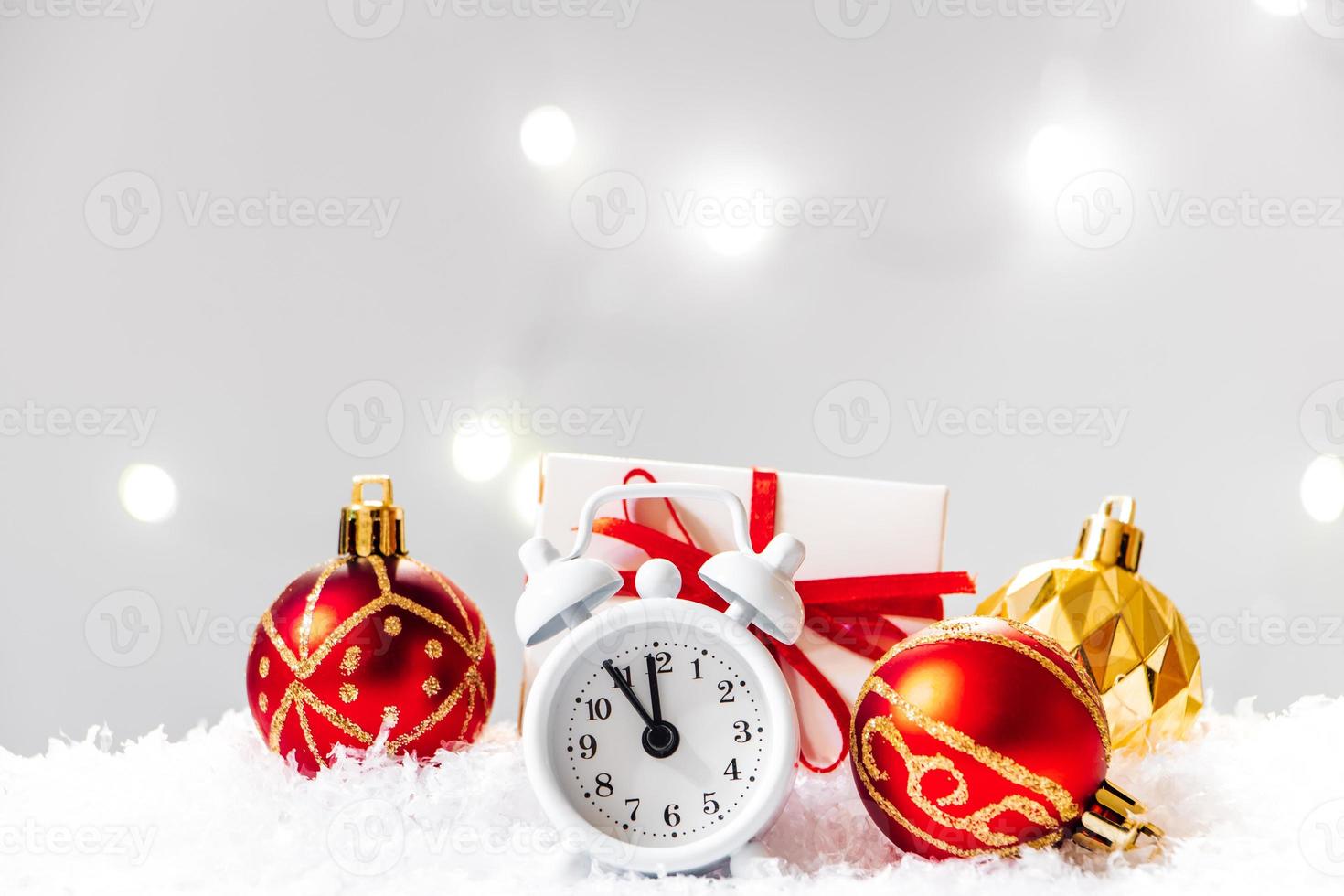 Christmas ball and alarm clock in the snow. New Year concept on background of garland lights. photo