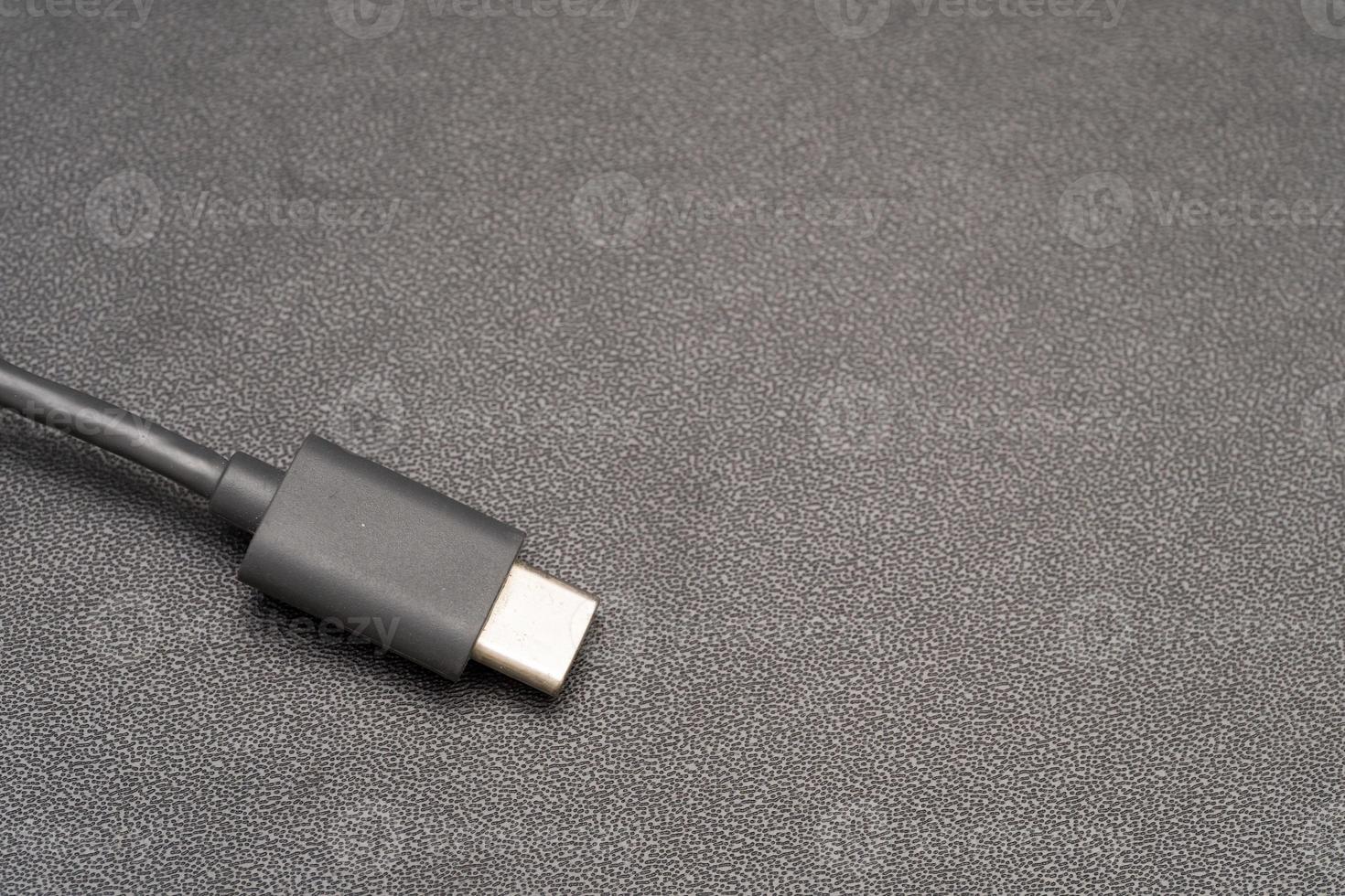 Close up of USB Type C connector with a grey cable on a dark background. Side close-up photo of grey type-c cable.