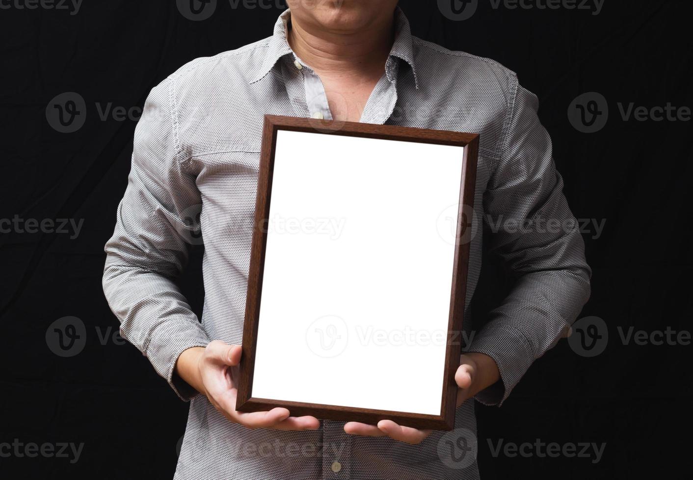 un diploma en blanco o un certificado de maqueta en la mano de un empleado con pantalones de fondo negro. el marco de imagen vertical está vacío y el espacio de copia. foto