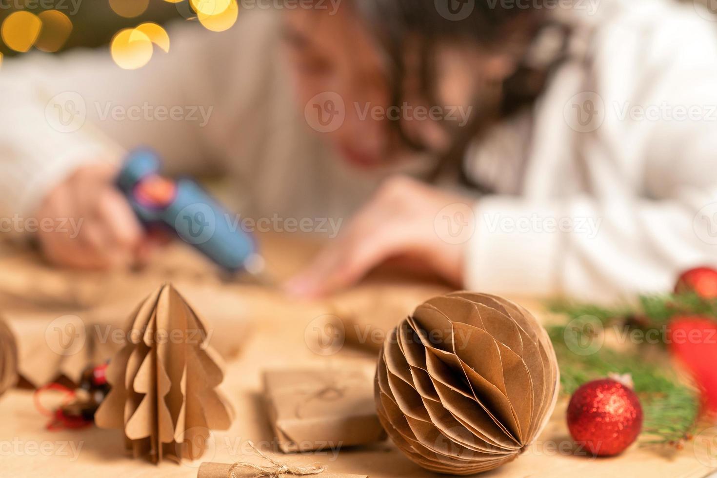 girl makes Christmas tree decorations out of paper with her own hands. step-by-step instruction photo