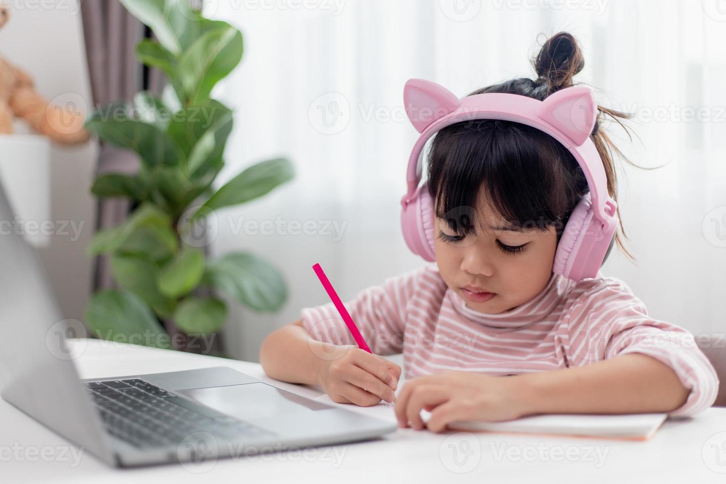Asian little girl in headphones have video call distant class with teacher using laptop, study online on computer, homeschooling concept photo