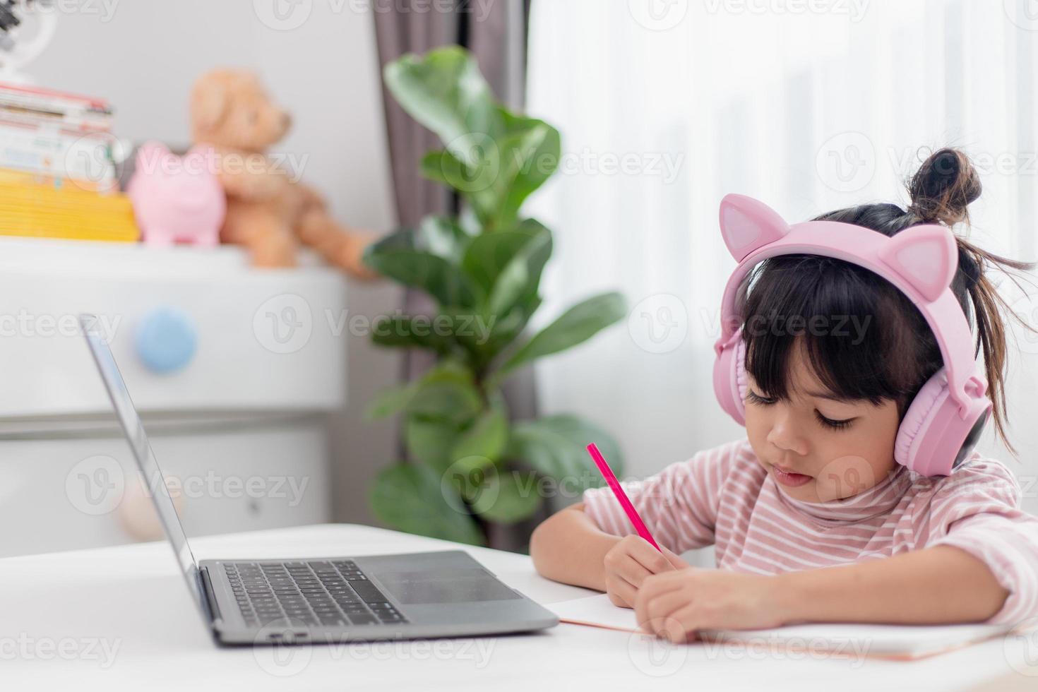 Asian little girl in headphones have video call distant class with teacher using laptop, study online on computer, homeschooling concept photo