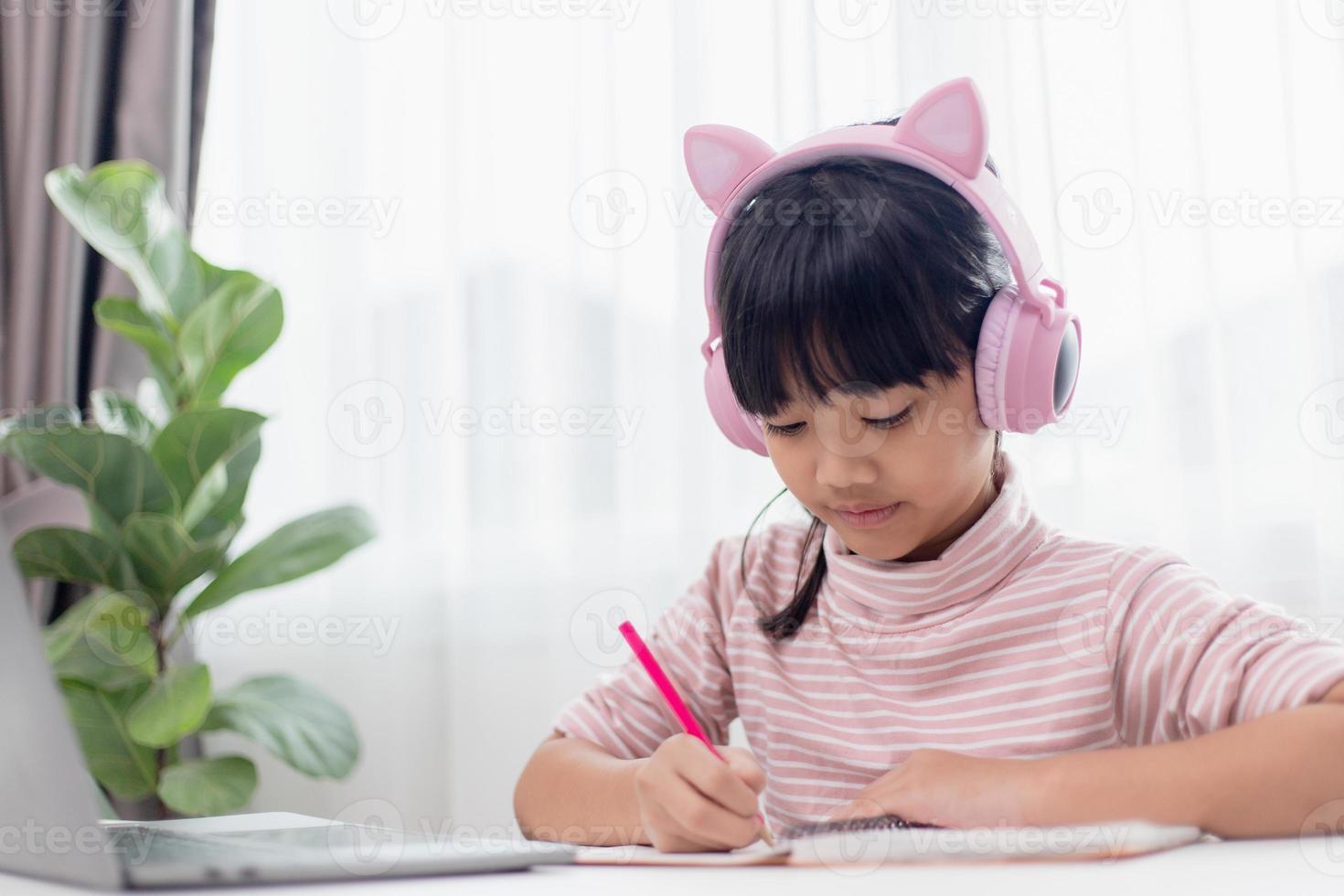 Asian little girl in headphones have video call distant class with teacher using laptop, study online on computer, homeschooling concept photo