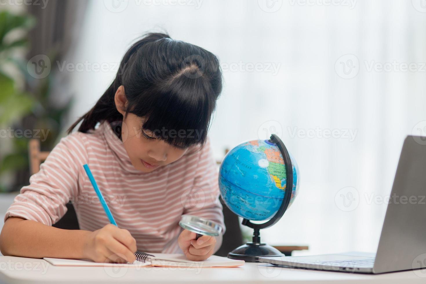 Asian little girl is learning the globe model, concept of save the world and learn through play activity for kid education at home. photo