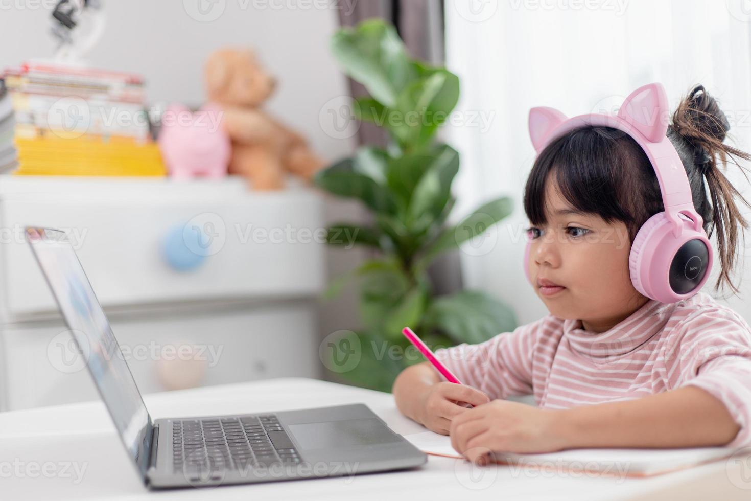 Asian little girl in headphones have video call distant class with teacher using laptop, study online on computer, homeschooling concept photo