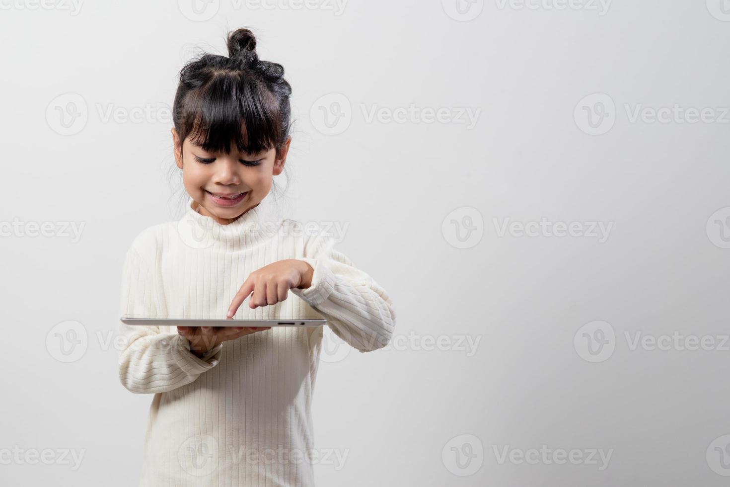 Asian little girl holding and using the digital tablet on white studio background, free copy space photo