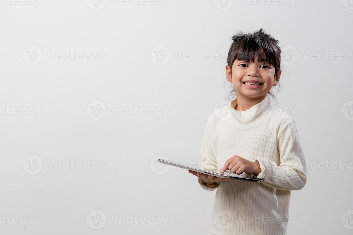 Asian little girl holding and using the digital tablet on white studio background, free copy space photo