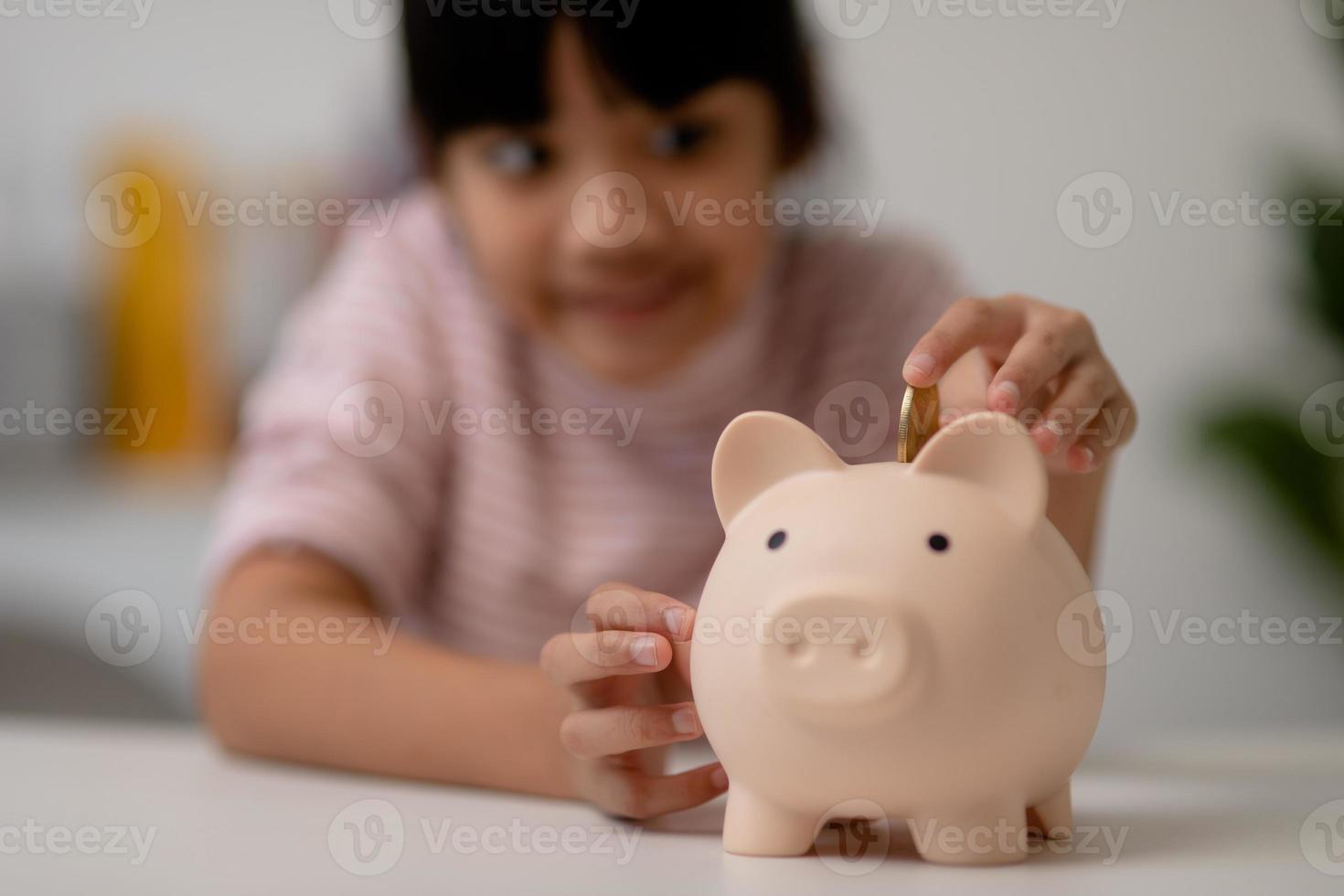 Little Asian girl saving money in a piggy bank, learning about saving, Kid save money for future education. Money, finances, insurance, and people concept photo