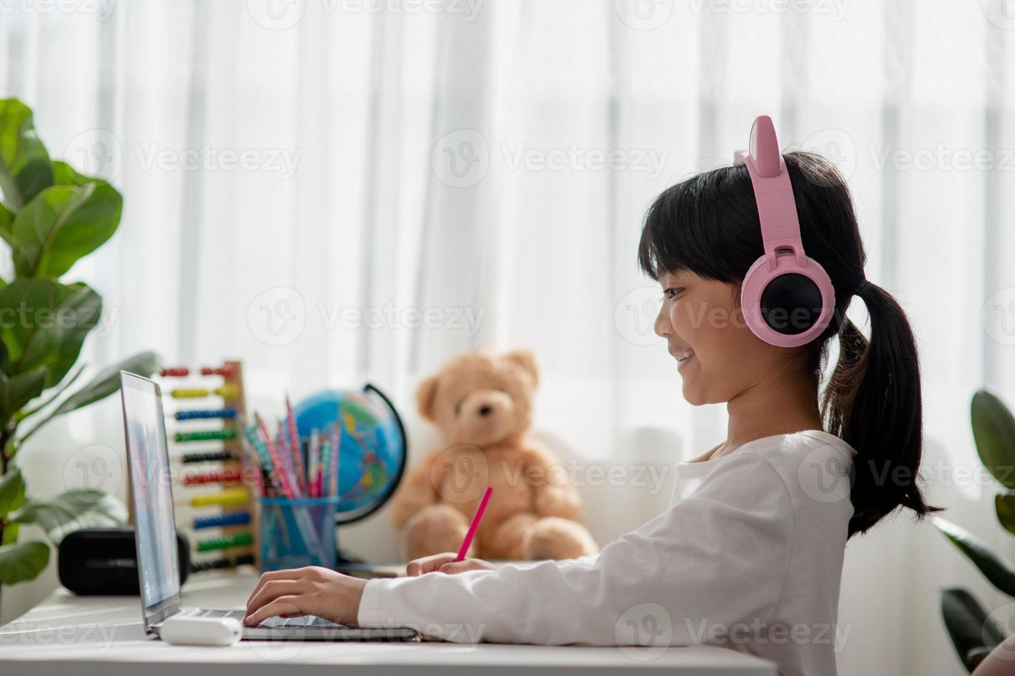 Asian little girl in headphones have video call distant class with teacher using laptop, study online on computer, homeschooling concept photo