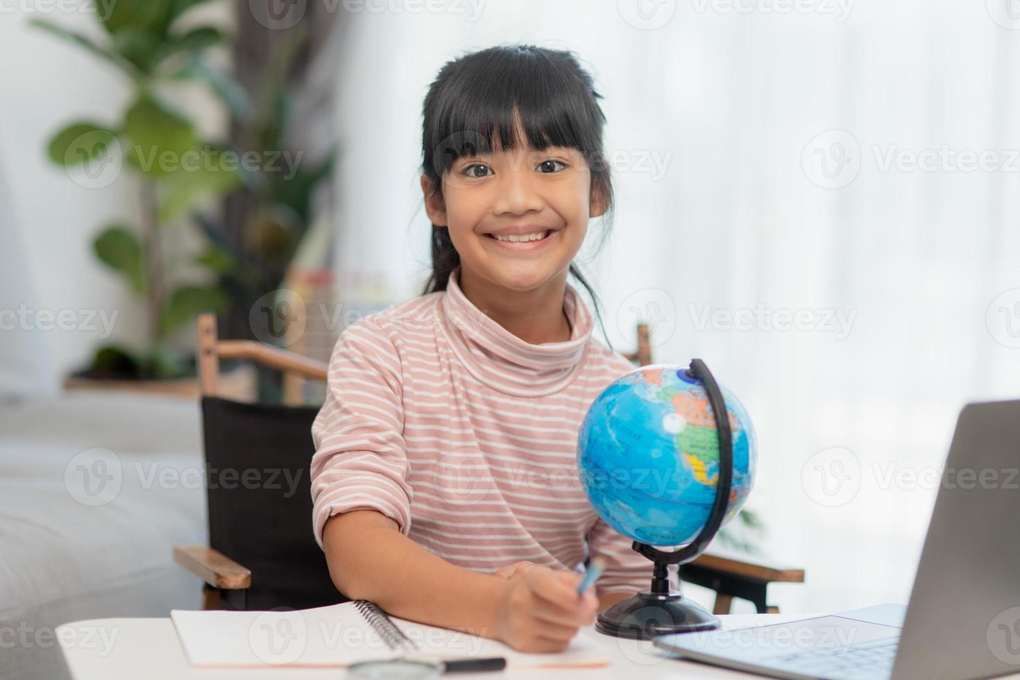 Asian little girl is learning the globe model, concept of save the world and learn through play activity for kid education at home. photo