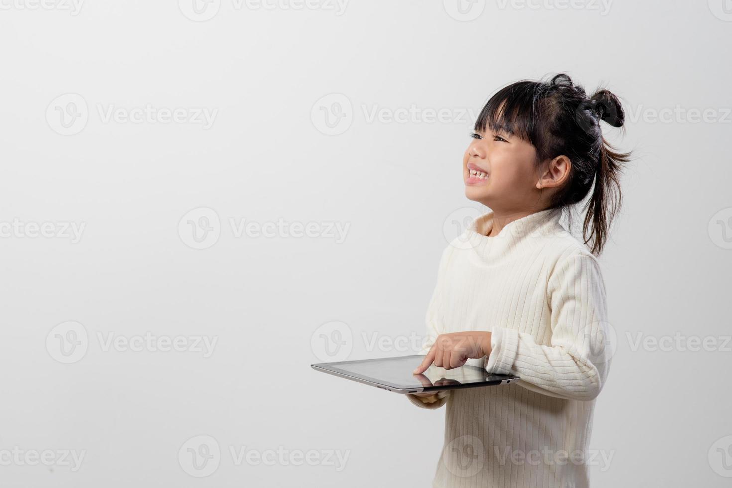 Asian little girl holding and using the digital tablet on white studio background, free copy space photo