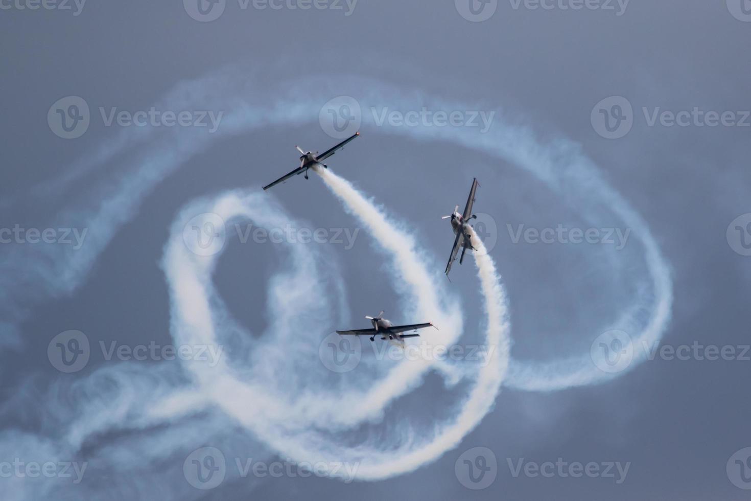 Three planes doing stunts at an airshow, with them billowing smoke photo