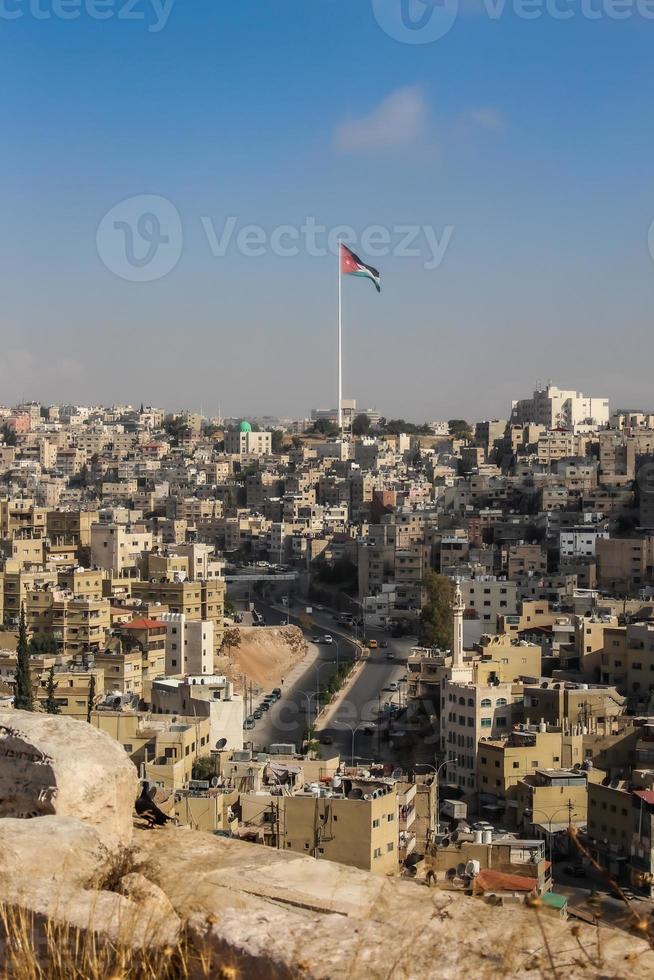 una vista de aman en jordania, con una bandera gigante ondeando sobre la ciudad foto