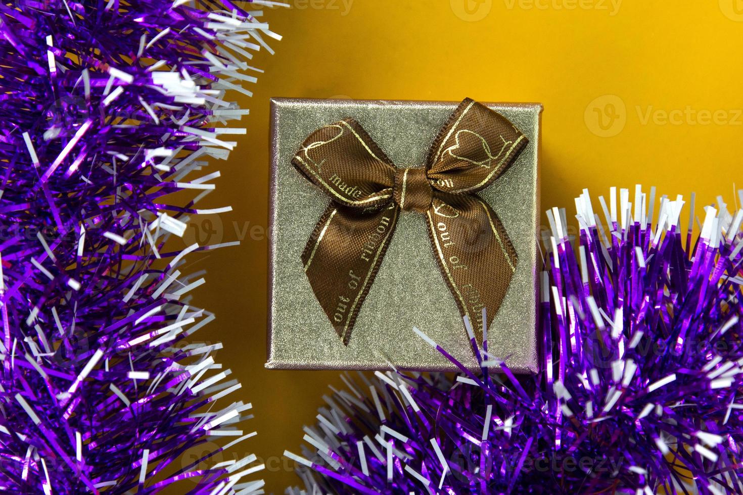 A Gift box isolated on yellow BG. a gift box with bright color ribbon and bow. used in celebration concept, christmas and new year banners photo