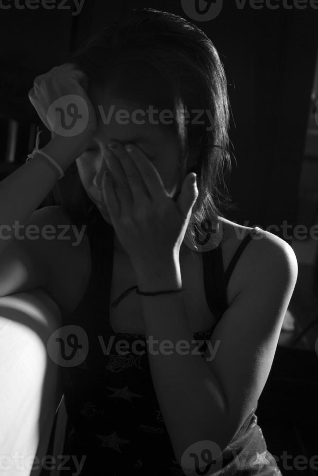 Sad and crying Asian girl sitting near bed in bedroom. and sexual harassment concept Asian women and violence against women in black and white. photo