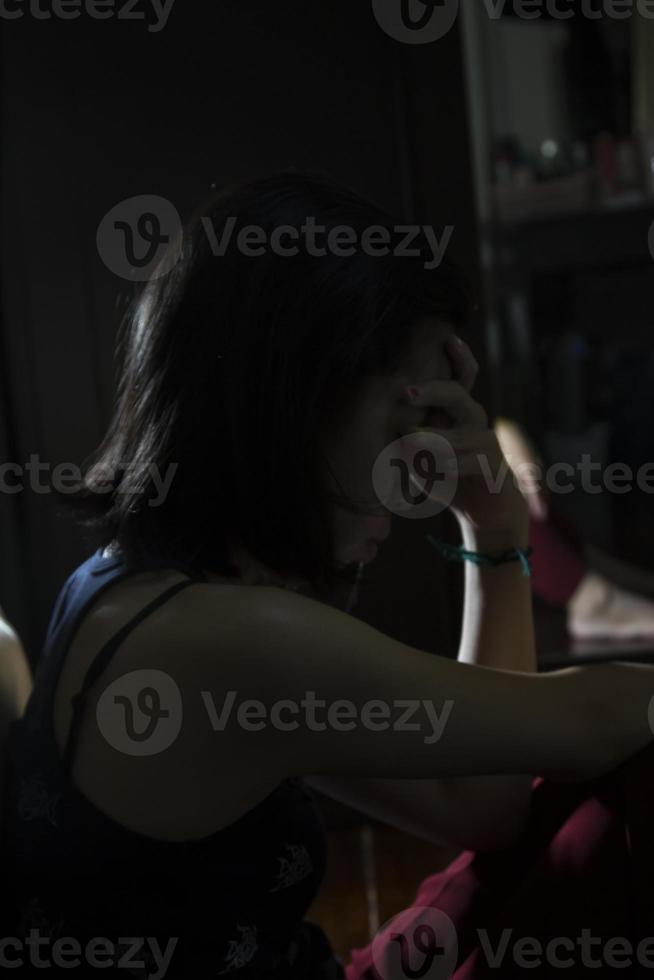 una silueta de una chica asiática de cerca en la habitación oscura que está triste y deprimida sola, una mujer triste sentada sola, una chica asiática con el corazón roto. foto
