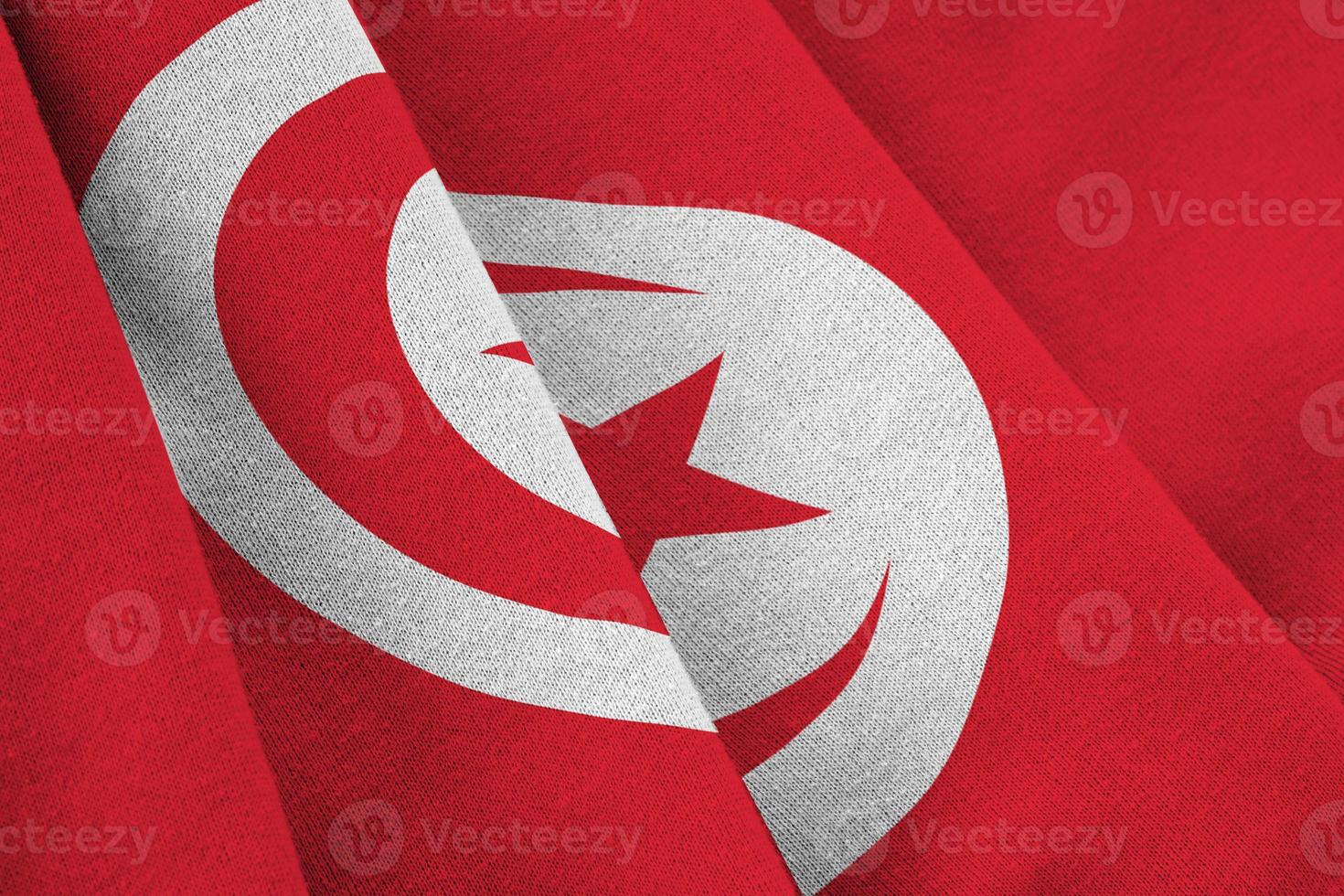 Tunisia flag with big folds waving close up under the studio light indoors. The official symbols and colors in banner photo