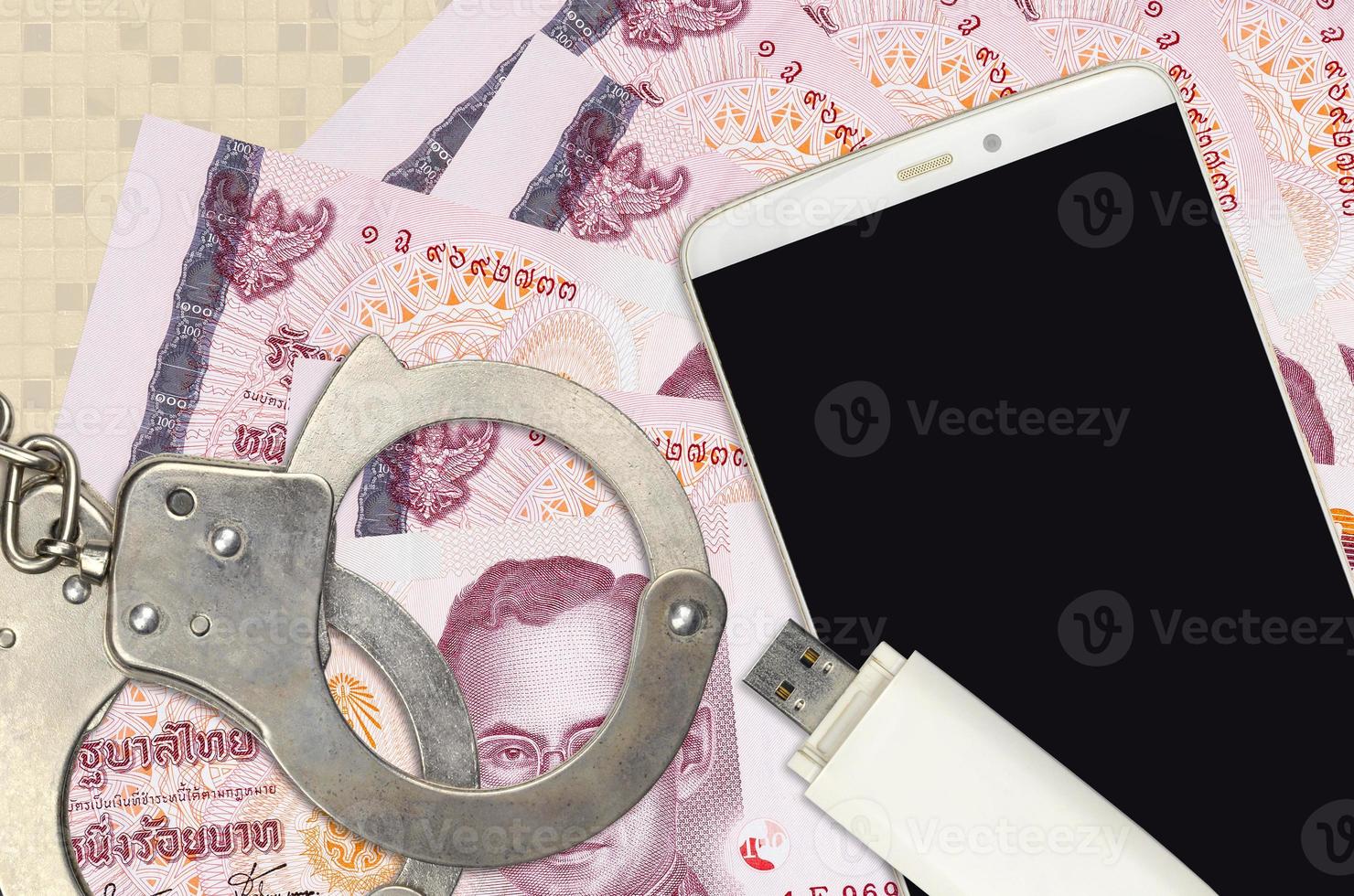 100 Thai Baht bills and smartphone with police handcuffs. Concept of hackers phishing attacks, illegal scam or malware soft distribution photo