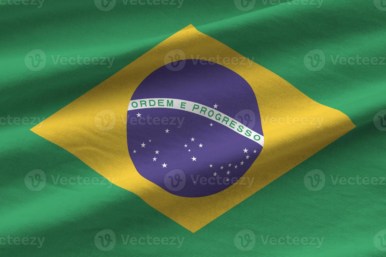 Brazil flag with big folds waving close up under the studio light indoors. The official symbols and colors in banner photo