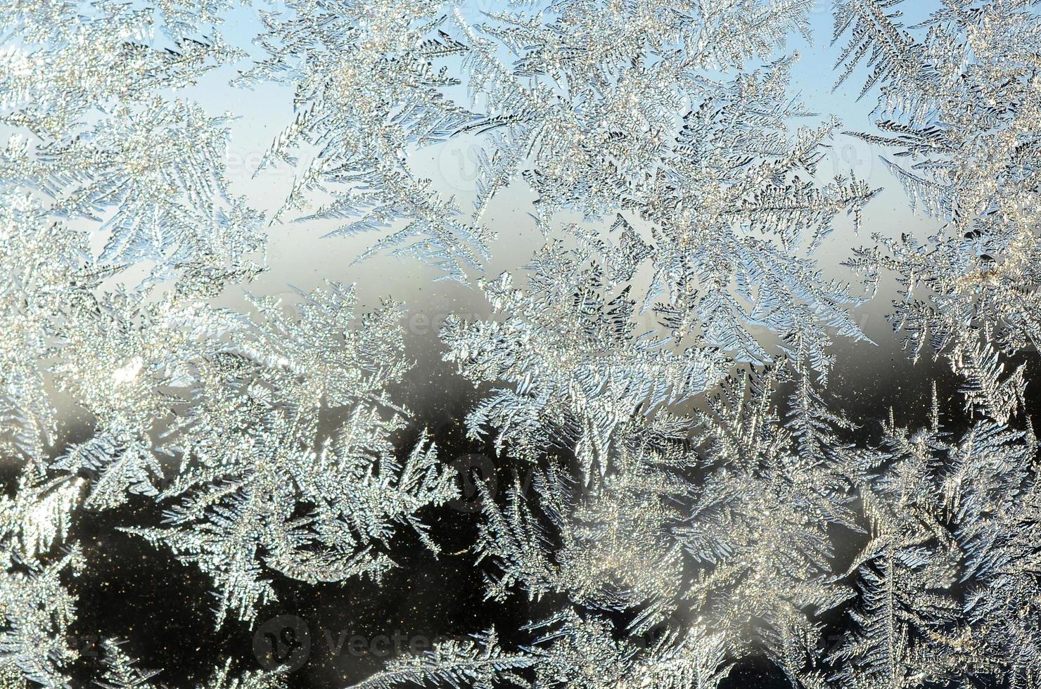 Snowflakes frost rime macro on window glass pane photo