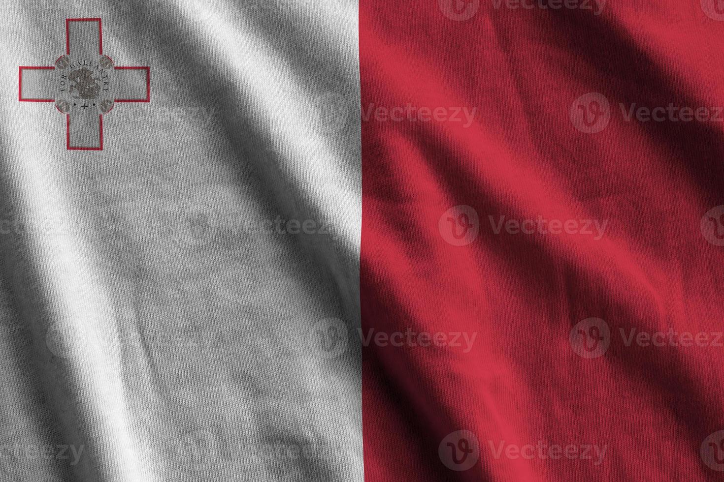 Malta flag with big folds waving close up under the studio light indoors. The official symbols and colors in banner photo