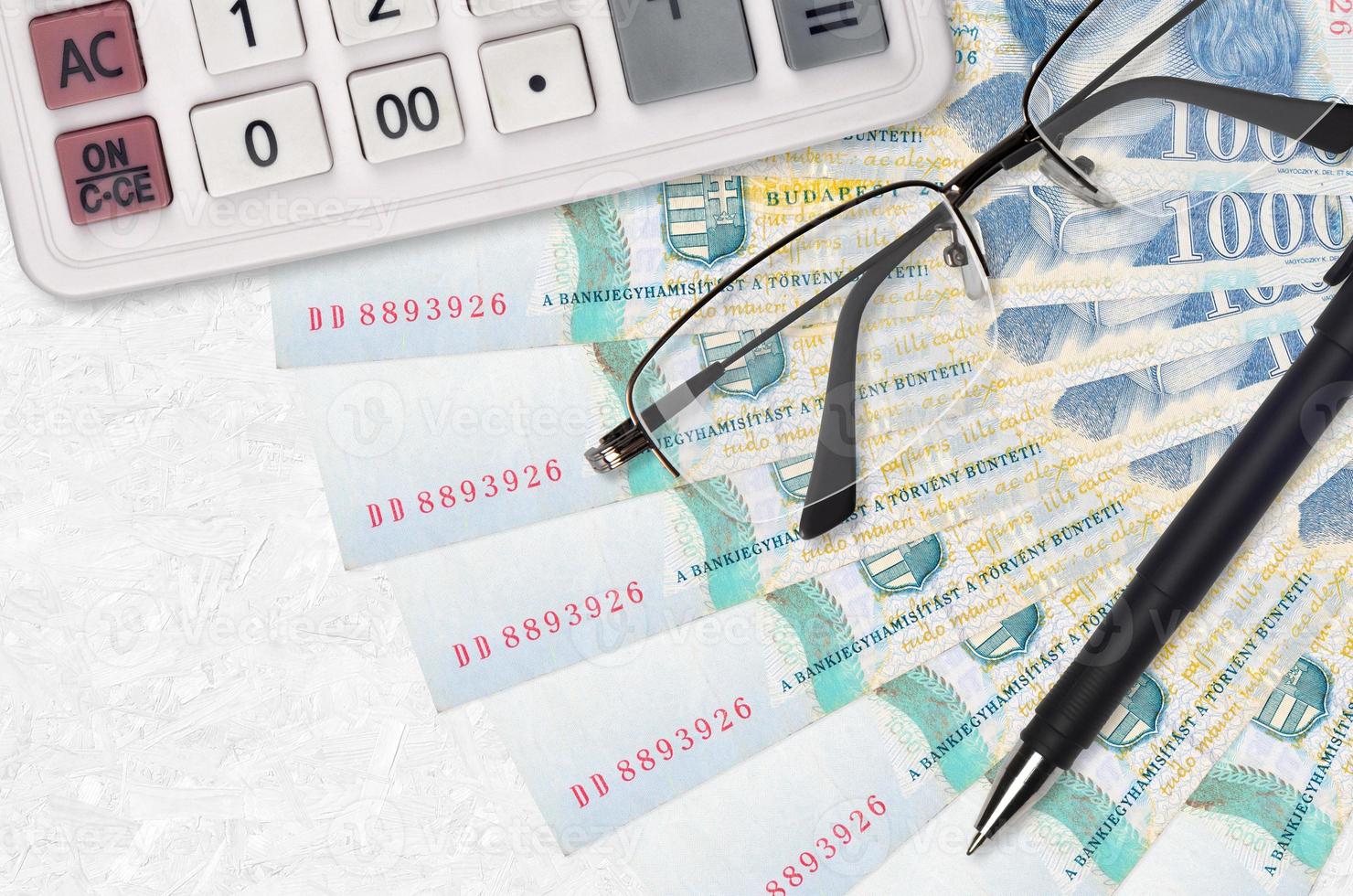 1000 Hungarian forint bills fan and calculator with glasses and pen. Business loan or tax payment season concept photo
