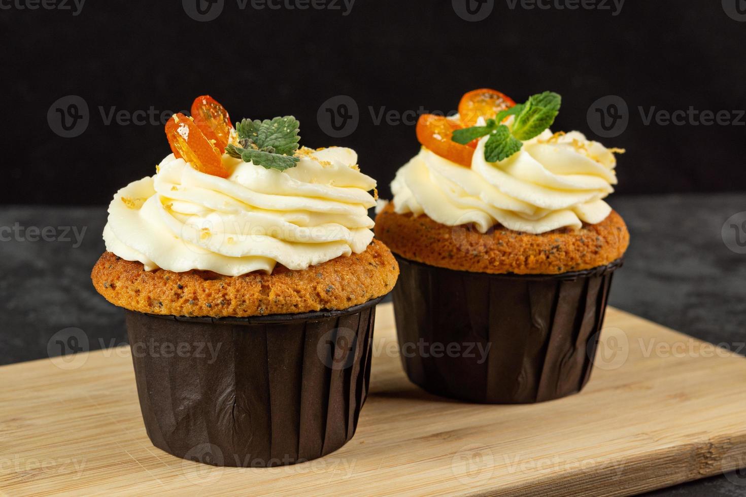 Cupcakes with cheese cream decorated with berries on dark background photo