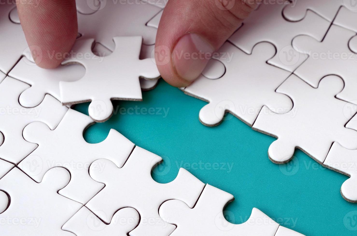 The human hand paves the way to the surface of the jigsaw puzzle, forming a blue space. The concept of overcoming the difficulties on the way to success photo