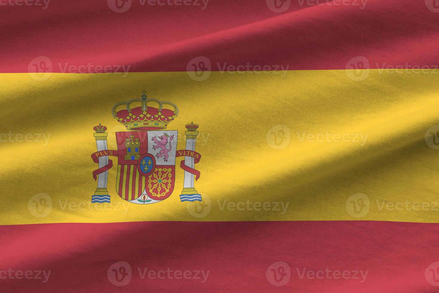 Spain flag with big folds waving close up under the studio light indoors. The official symbols and colors in banner photo