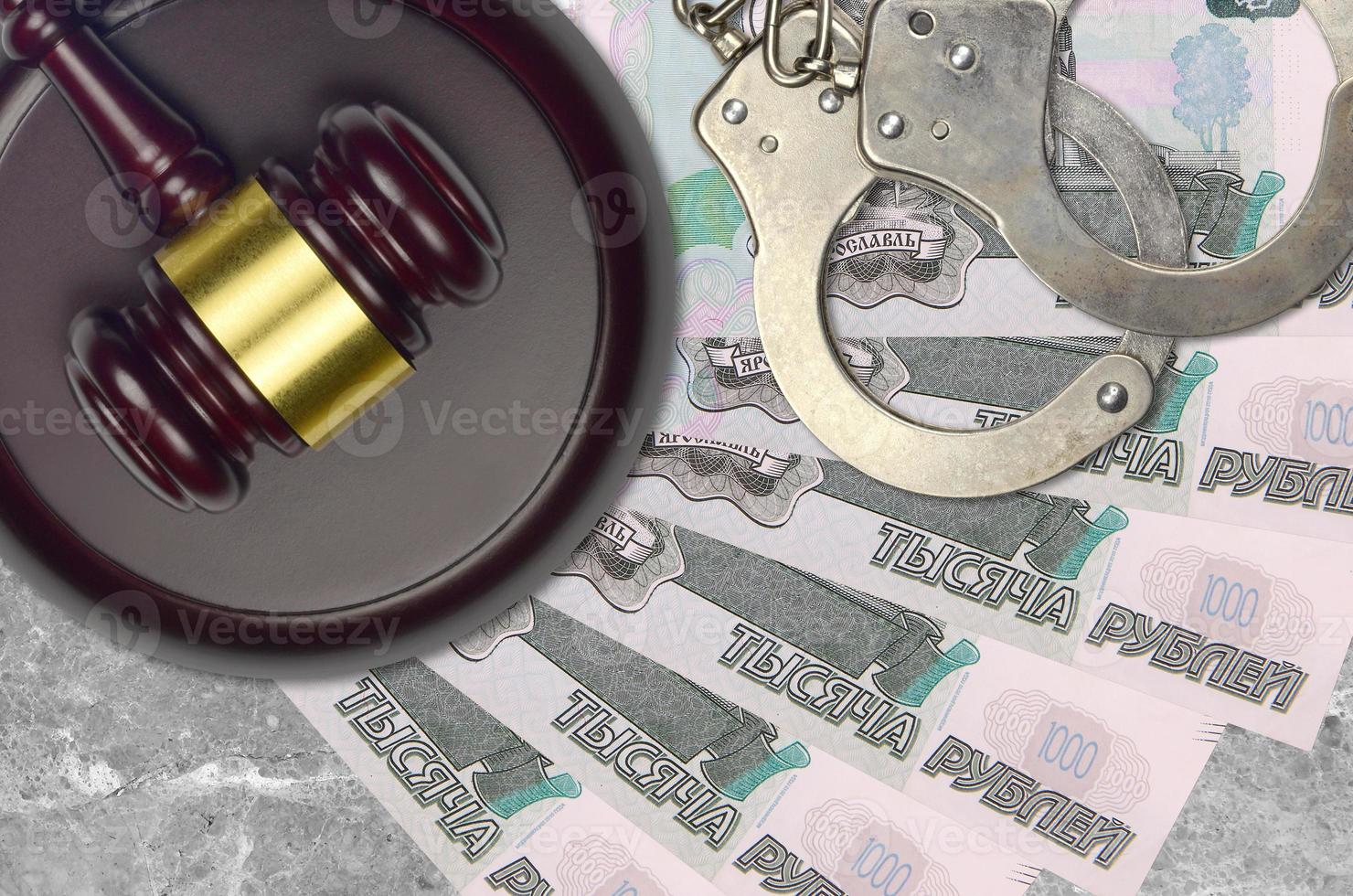 1000 russian rubles bills and judge hammer with police handcuffs on court desk. Concept of judicial trial or bribery. Tax avoidance photo