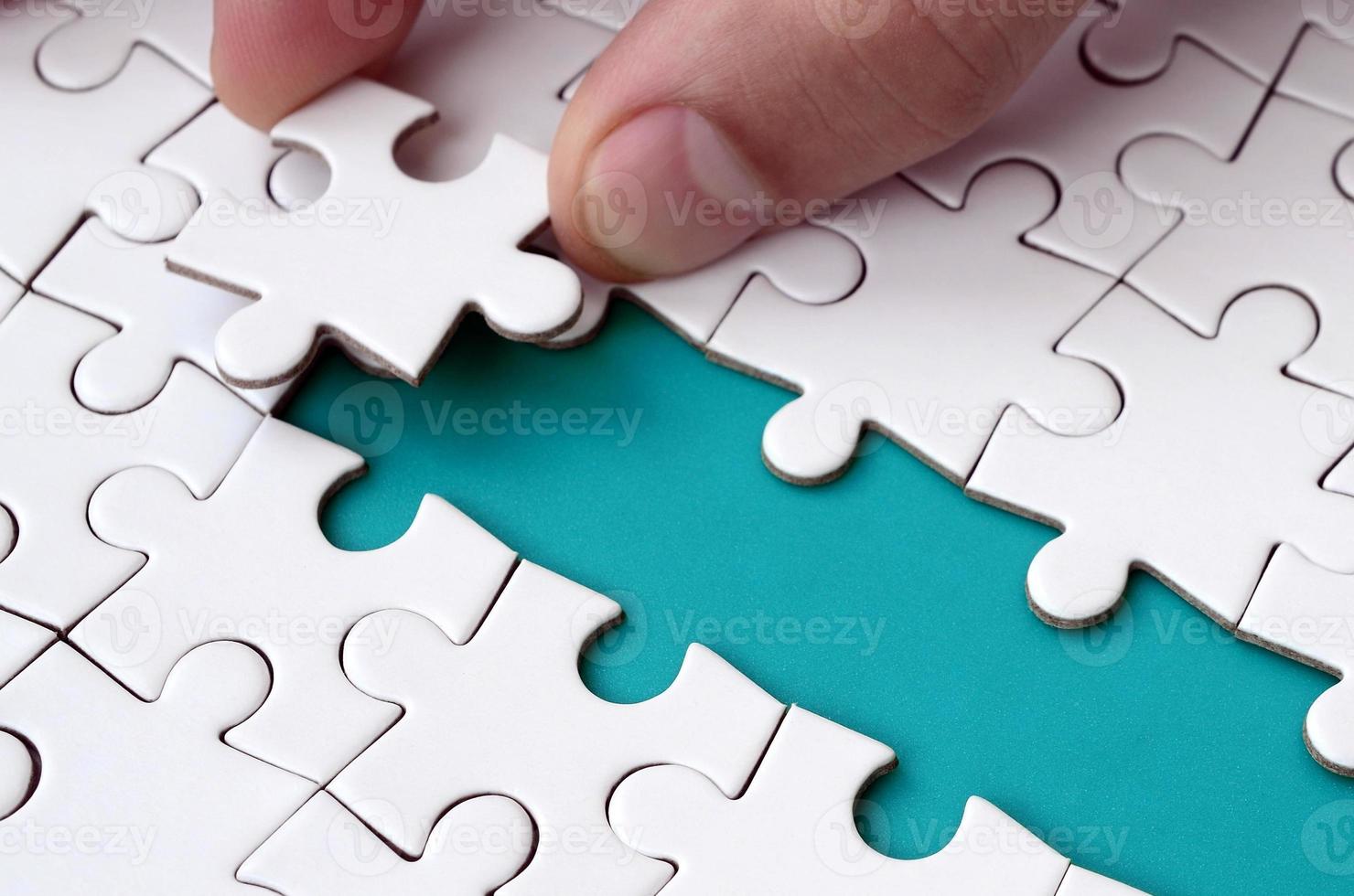 The human hand paves the way to the surface of the jigsaw puzzle, forming a blue space. The concept of overcoming the difficulties on the way to success photo