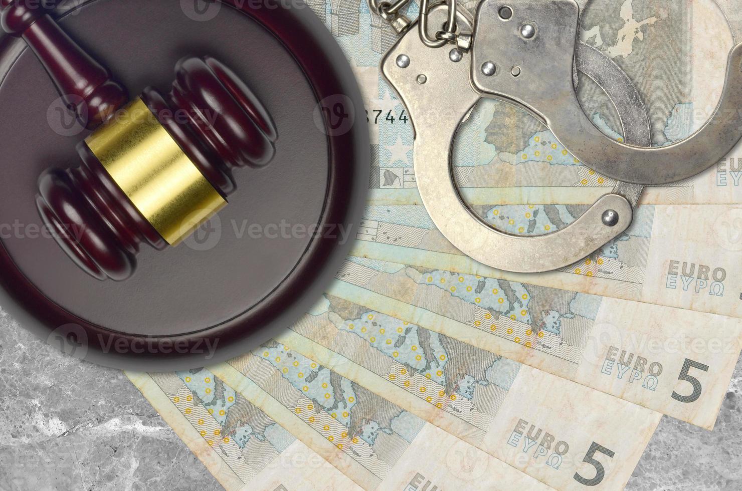 5 euro bills and judge hammer with police handcuffs on court desk. Concept of judicial trial or bribery. Tax avoidance photo
