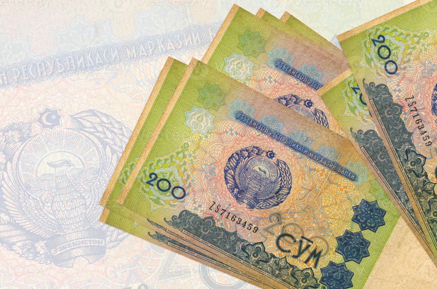 200 Uzbekistani som bills lies in stack on background of big semi-transparent banknote. Abstract presentation of national currency photo