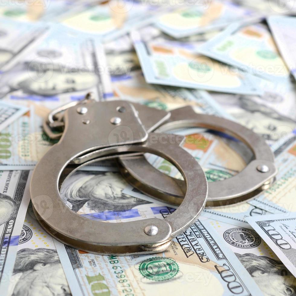 Silver police handcuffs lies on a many dollar bills photo