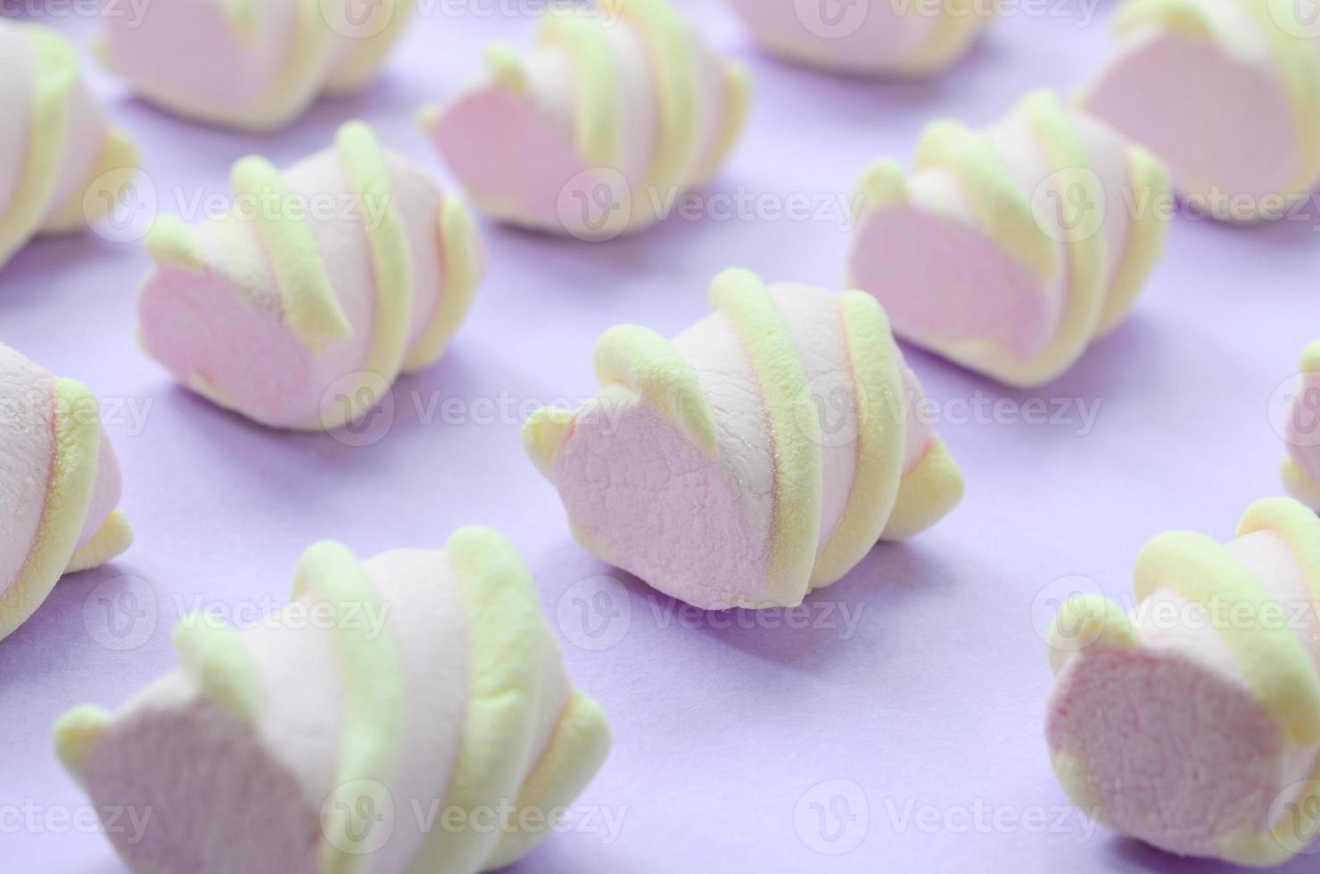 Colorful marshmallow laid out on violet paper background. pastel creative textured pattern. Perspective macro shot photo