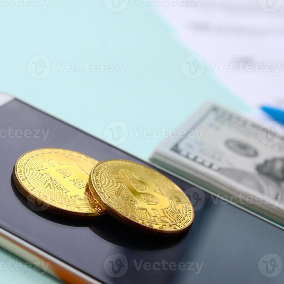 Bitcoins lies with the tax forms, hundred dollar bills and smartphone on a light blue background. Income tax return photo