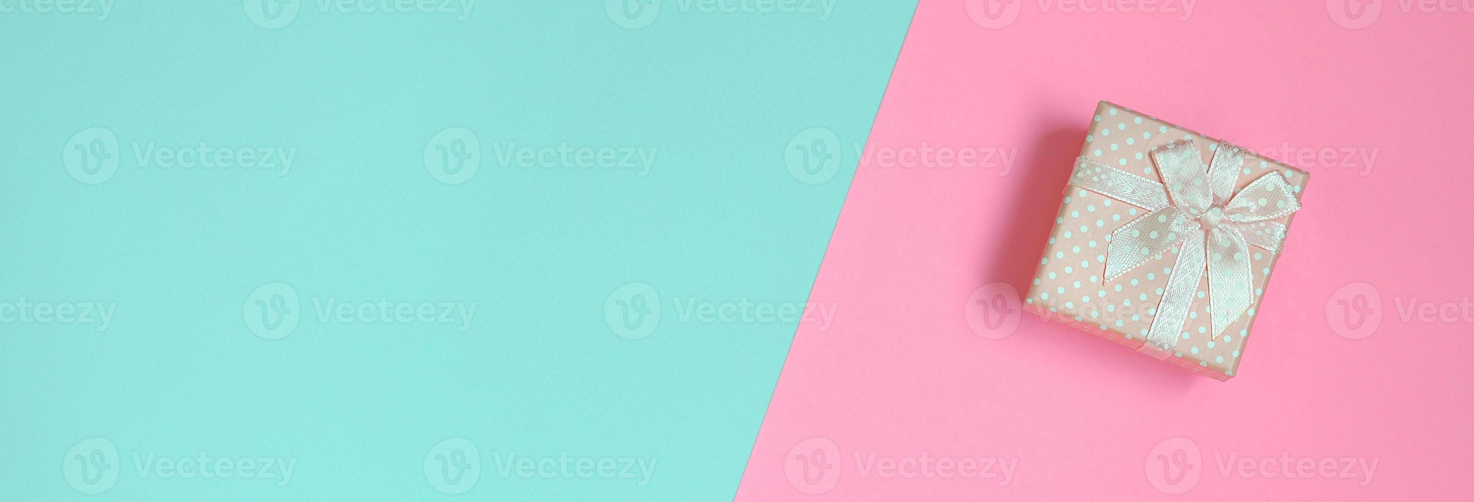 Small pink gift box lie on texture background of fashion pastel blue and pink colors paper in minimal concept photo