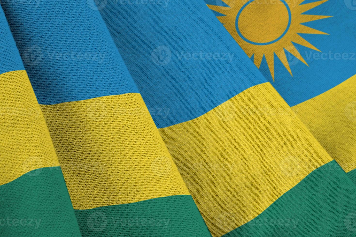 Rwanda flag with big folds waving close up under the studio light indoors. The official symbols and colors in banner photo