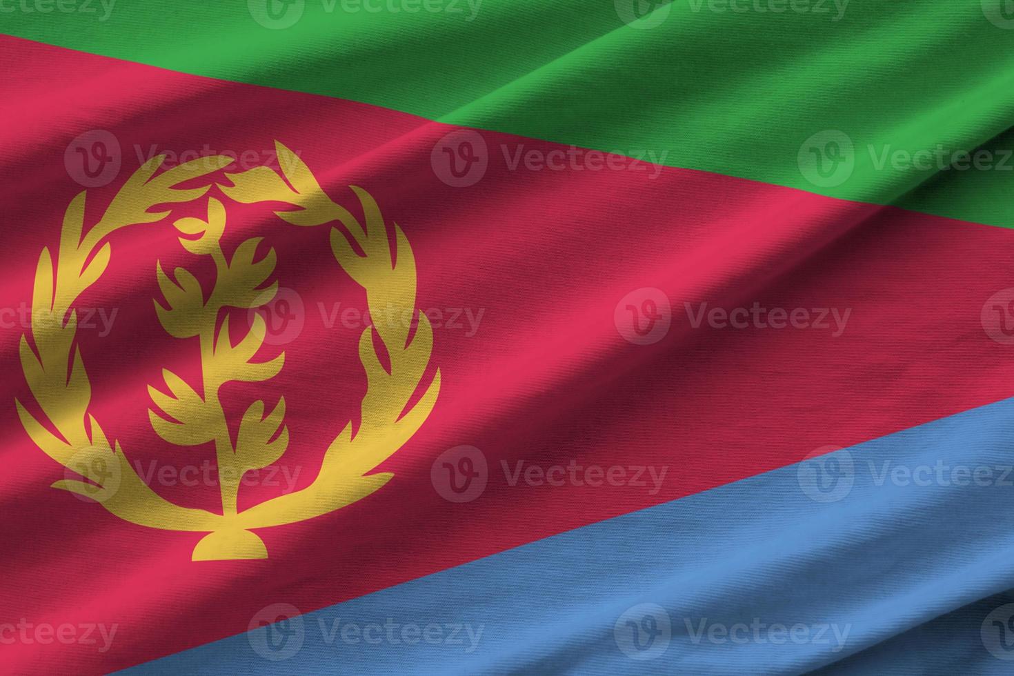 Eritrea flag with big folds waving close up under the studio light indoors. The official symbols and colors in banner photo