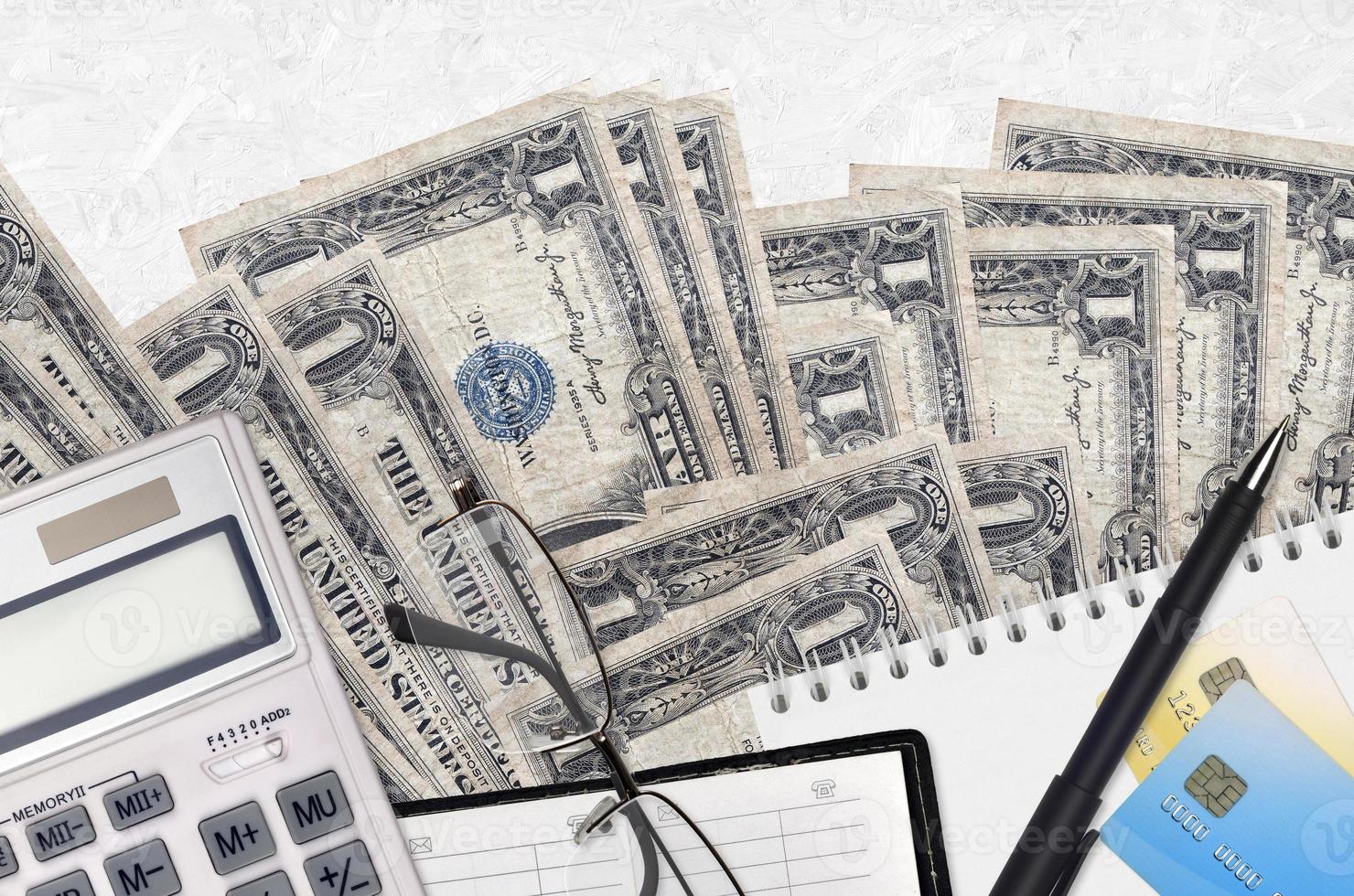 1 US dollar bills and calculator with glasses and pen. Tax payment concept or investment solutions. Financial planning or accountant paperwork photo