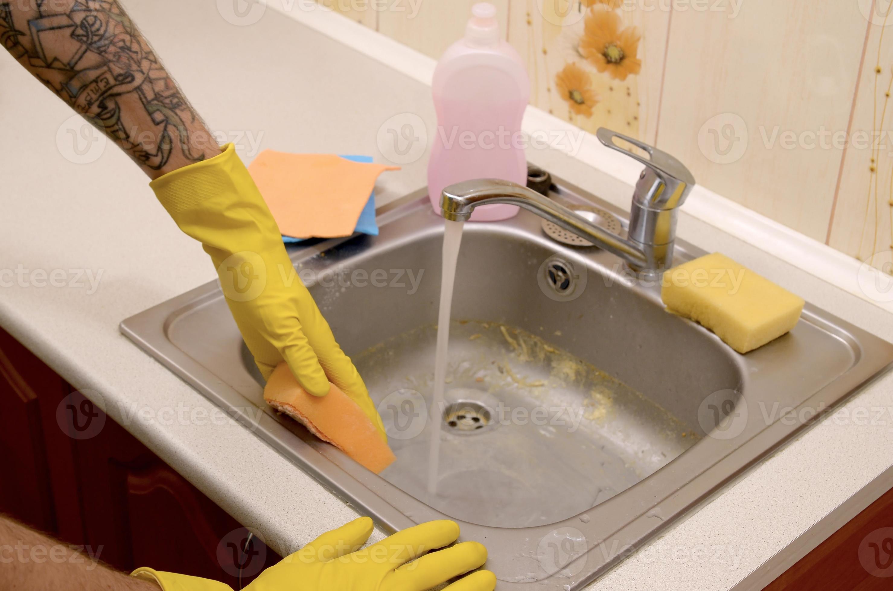 Person or householder cleaning the kitchen sink with sponge in close up