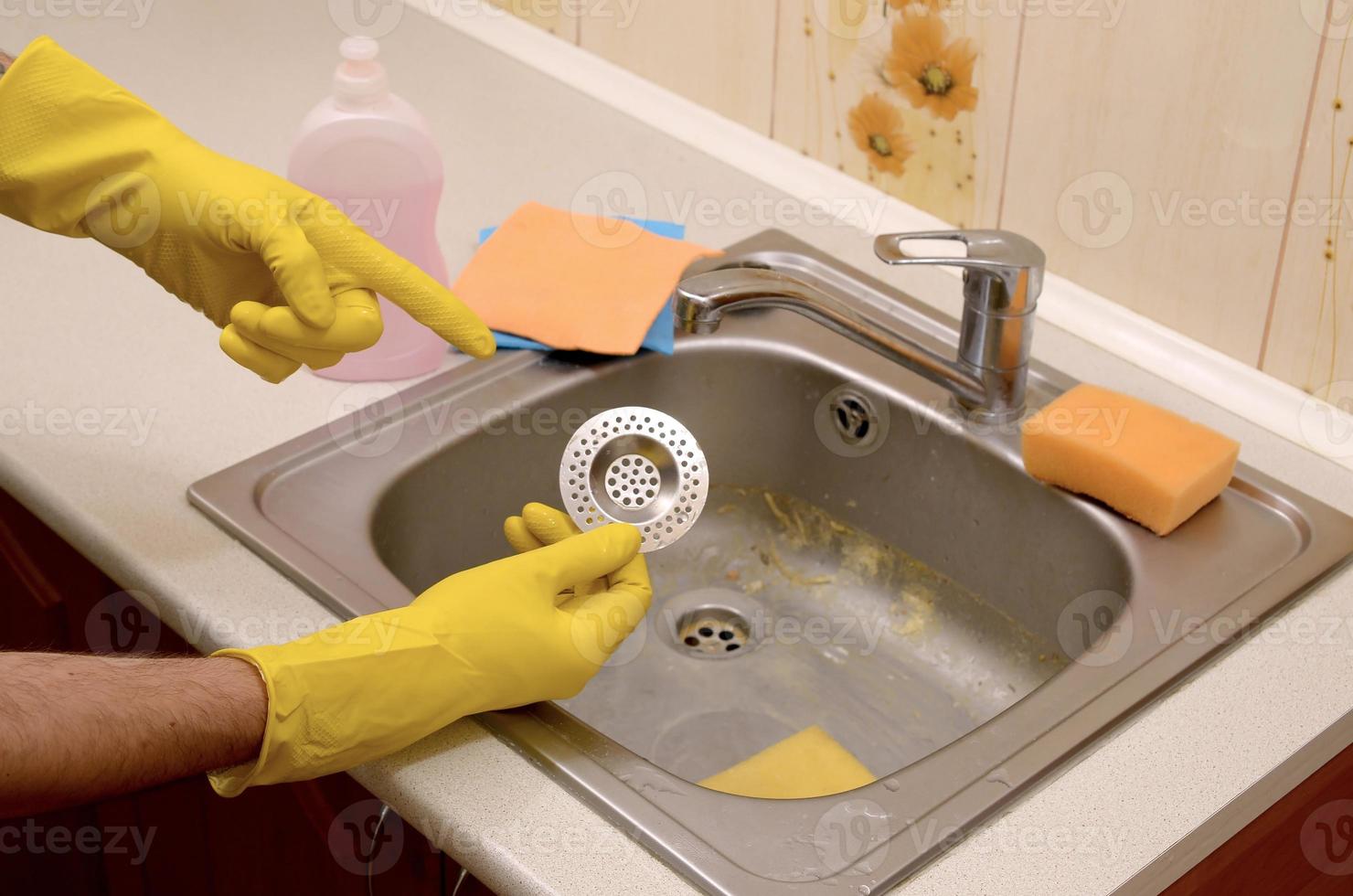 Cleaner in rubber gloves shows clean plughole protector of a kitchen sink photo