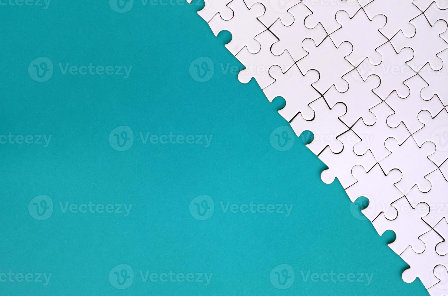 Fragment of a folded white jigsaw puzzle on the background of a blue plastic surface. Texture photo with copy space for text