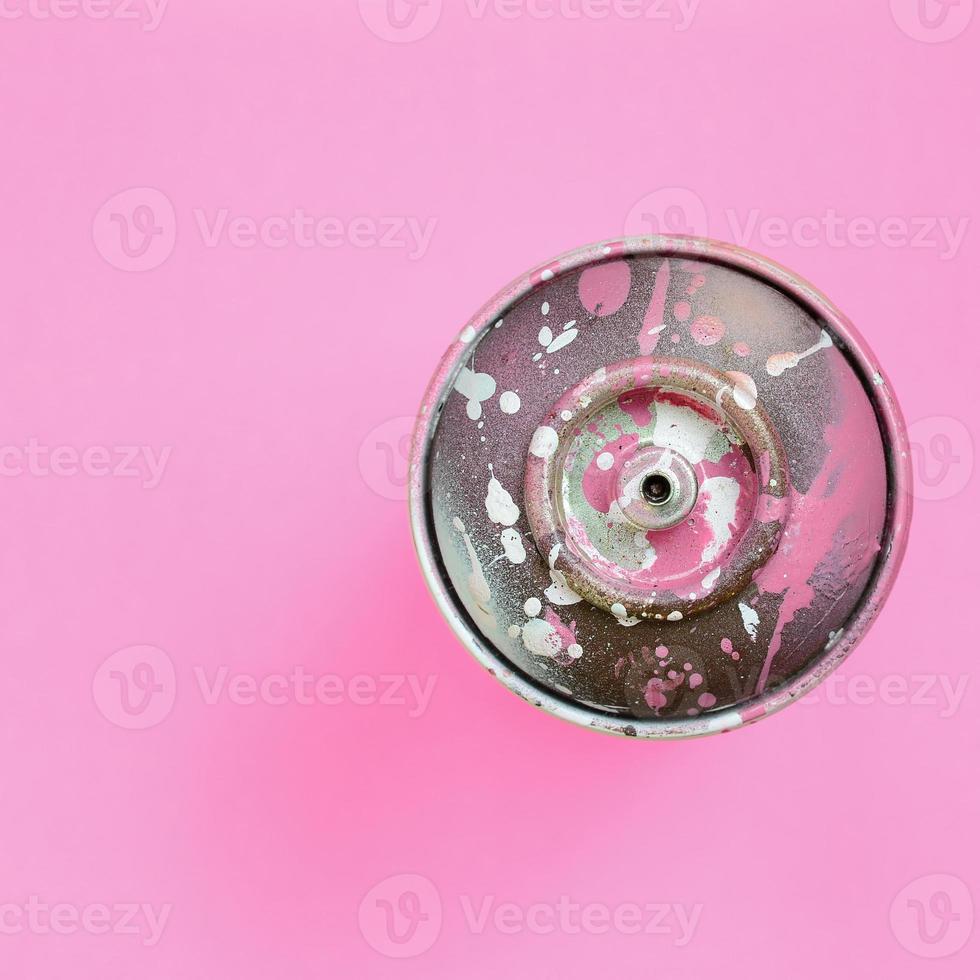 lata de aerosol usada con gotas de pintura rosa se encuentran en el fondo de textura de papel de color rosa pastel de moda en un concepto mínimo foto