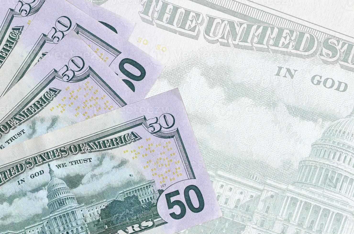 50 US dollars bills lies in stack on background of big semi-transparent banknote. Abstract business background photo