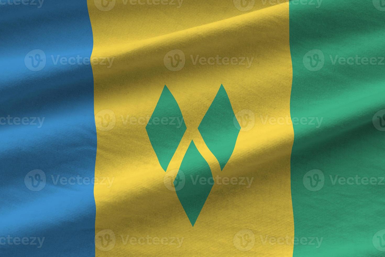Saint Vincent and the Grenadines flag with big folds waving close up under the studio light indoors. The official symbols and colors in banner photo