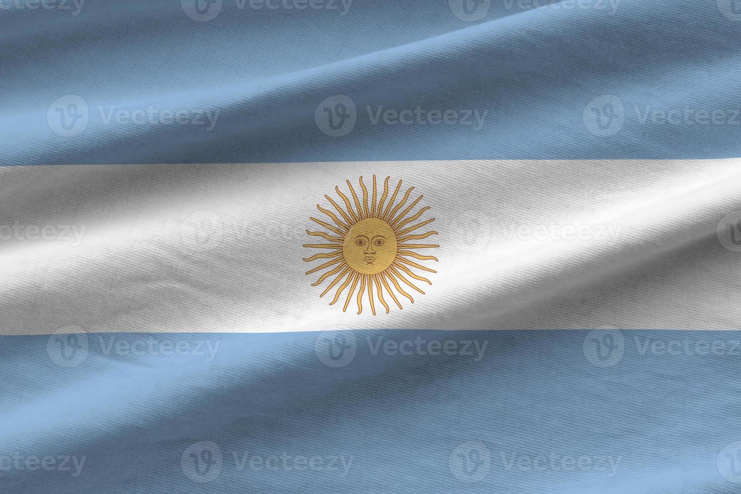 Argentina flag with big folds waving close up under the studio light indoors. The official symbols and colors in banner photo
