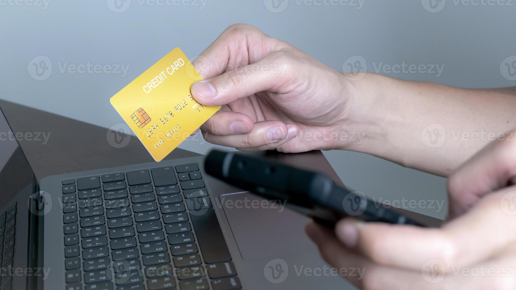 Hands holding credit card and using laptop or mobile,Online shopping, e-commerce, internet banking, spending money, working from home concept photo