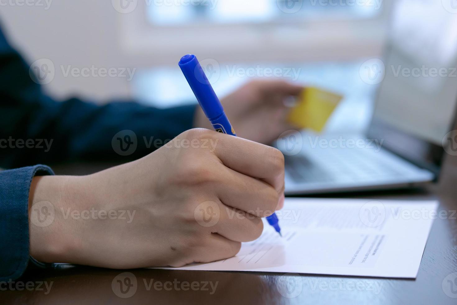 Close up hand using pen for writing on paper,hand holding credit card background with tablet,business concept. photo